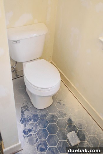 Our Bathroom's Wallpaper Detox 12 Person sanding spackled wall with a sanding block, demonstrating dust in the air.
