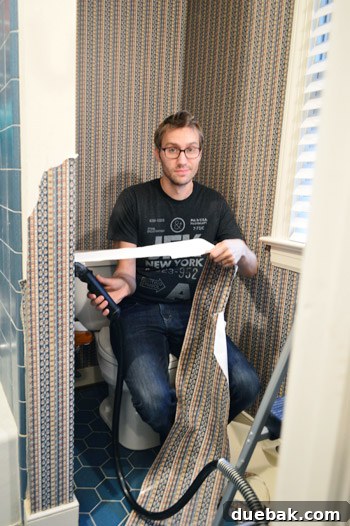 Our Bathroom's Wallpaper Detox 6 Person still working on wallpaper removal, looking tired, with messy hair and glasses.