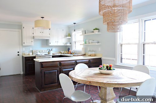 Kitchen's Gilded Past 5 Old white kitchen chairs, previously used, appear small next to a chunky wooden dining table.