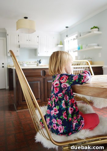 Kitchen's Gilded Past 10 Another view of a child on a comfortable vintage wire kitchen chair, adding a personal touch to the dining experience.