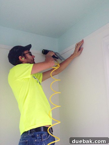 Bathroom Ceiling Transformation with Paint and Trimwork 8 Installing lattice trim with a nail gun, ensuring level placement in the bathroom renovation.