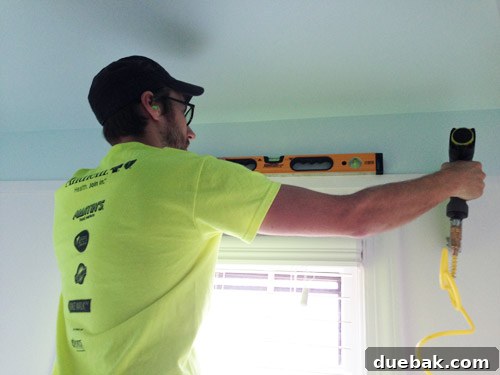 Bathroom Ceiling Transformation with Paint and Trimwork 9 Teamwork: securing lattice trim with a nail gun while ensuring level alignment in the bathroom.