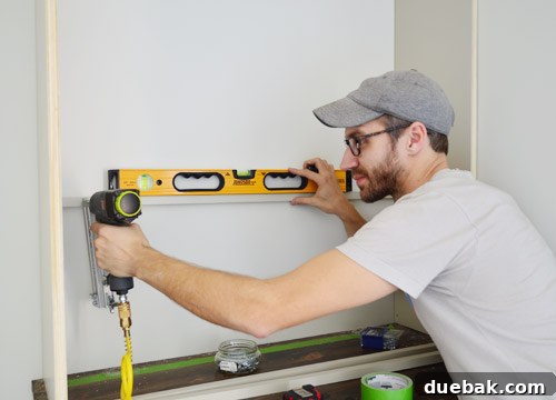 Craft Your Own Library Haven 12 A person using a level to accurately nail in shelf support pieces onto the frame of a DIY bookshelf, ensuring even and stable shelf placement.