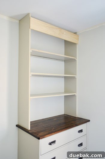 Craft Your Own Library Haven 13 Pre-painted shelves being carefully placed into the partially constructed frame of a DIY bookshelf, showing the progression of the build.