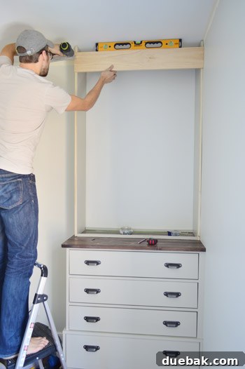 Craft Your Own Library Haven 10 A person carefully adding a temporary trim piece to the top of a custom bookshelf frame, ensuring it's square and stable during construction.