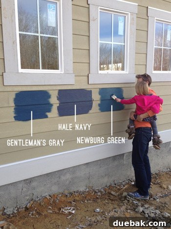 Child observing paint test samples on house siding
