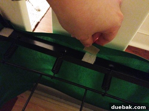 Attaching the DIY crib skirt to the crib frame using velcro tabs