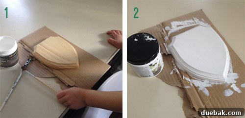 A child painting a small wooden craft plaque white