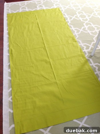 Backside view of a completed curtain panel laid on the floor, showing all hems and fabric texture.