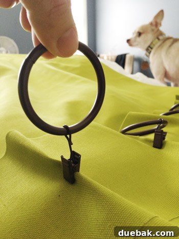 Detailed shot of curtain clips attached to the back of the curtain's thick top hem to form pleats.