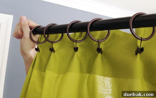 John holding curtain rod with one panel, demonstrating backside clip attachment for pleats.