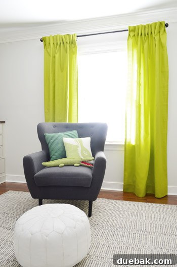 Front view of the newly installed apple green pinch pleat curtains in the nursery, fully hung.