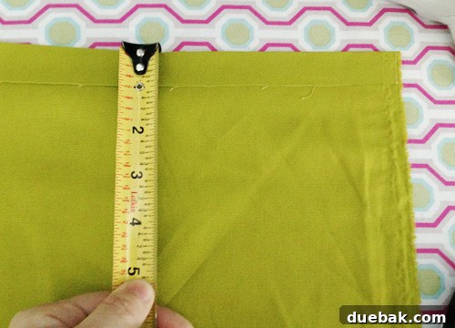 Detailed view of applying Heat N' Bond hem tape to create the initial 1-inch fold on curtain fabric.