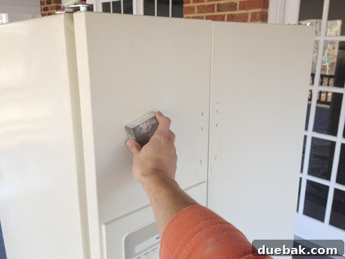 sanding fridge in preparation for paint