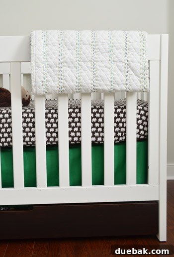 Hand-stitched baby quilt draped over a crib in a nursery