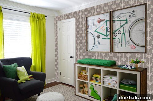 A wide-angle Photoshop mock-up showing the light patterned wallpaper on the accent wall within the full nursery room context, with crib and furniture.