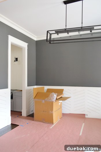 Dining room with dark wainscoting and modern chandelier.