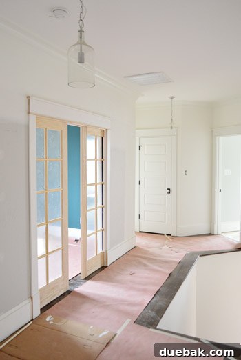 Upstairs hallway with glass jug pendants and a view of the stairs.