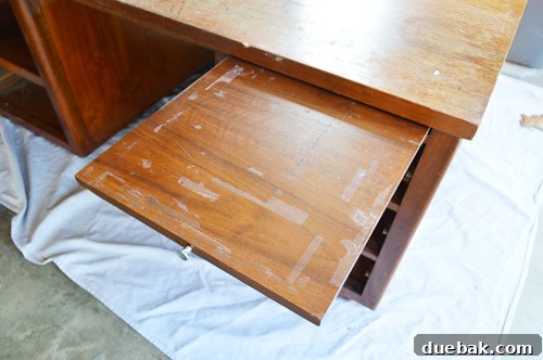 Scraping off old paint and glue from the desk surface using a straight razor.