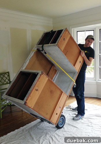 Moving the primed desk indoors using a dolly, to prevent damage during painting.