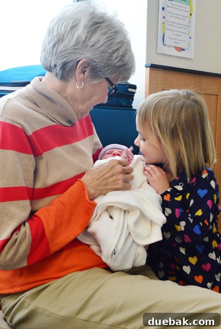 He Makes His Entrance 3 Big sister Clara lovingly snuggling her newborn baby brother Teddy, displaying a tender and protective embrace. Her affection for her new sibling is clear.
