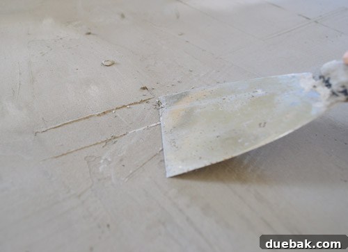 Sherry scraping high spots off dried Ardex with a putty knife