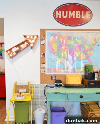 Home office craft room workspace, featuring a large map and a vintage arrow, showcasing a blend of functionality and eclectic decor.