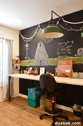 Large chalkboard wall provides a dynamic backdrop for a long desk crafted from repurposed doors, serving as a spacious art workspace.