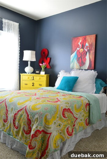 Fun bedroom design with a vibrant paisley bedspread and a yellow distressed dresser, creating a welcoming and eclectic guest space.