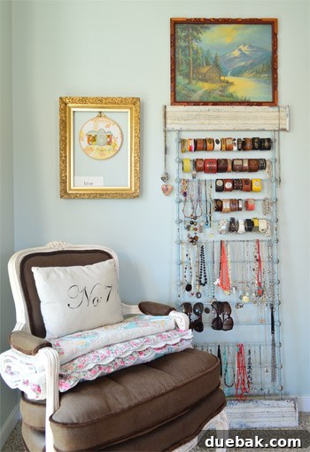 Creative jewelry display rack in the bedroom, complemented by a vintage chair and curated wall art, adding a unique touch.