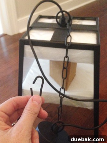 Installer holding a light fixture with a shortened chain, showing one link