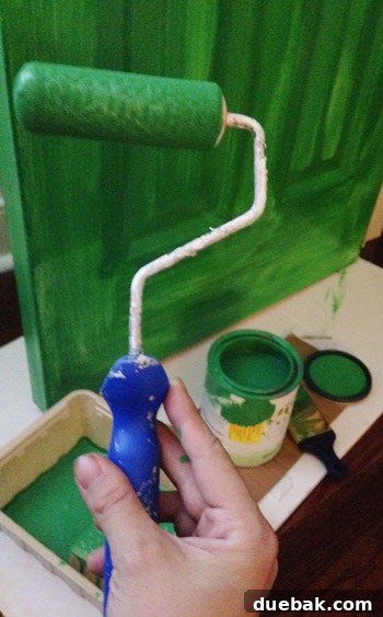 A Burst of Green Joy for the Nursery Closet 9 Second coat of green paint being applied to the closet door with a roller and brush