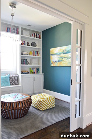 Crafting the Dream Showhouse 11 A playroom with built-in bookshelves and a window seat, decorated with books and games.