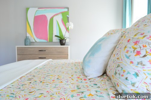 Crafting the Dream Showhouse 14 A beautifully made master bedroom with patterned bedding and a large painting.