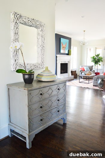 Crafting the Dream Showhouse 9 A modern foyer with a large white driftwood mirror and glimpses of the living room beyond.