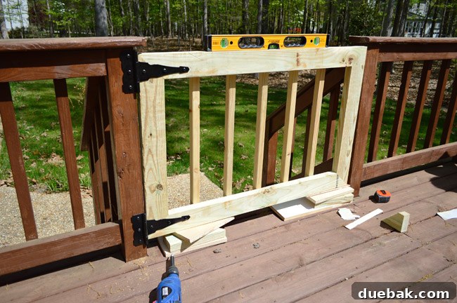 Deck Gate Installed Across Opening In Deck Railing Stairs using Level and Scrap Wood To Hold Into Place During Installation