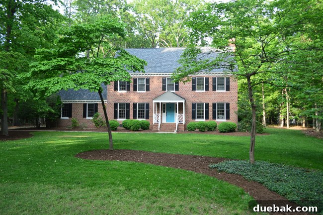 Front View Of Brick Colonial Home This Summer With Green Grass and Mulch Beds