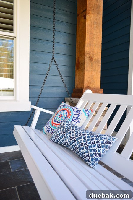 Porch swing with custom black chain from Hayneedle.com on the front porch.