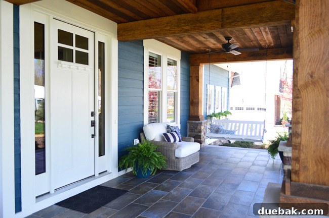 View of the second seating area on the front porch, featuring a porch swing and a swivel chair.