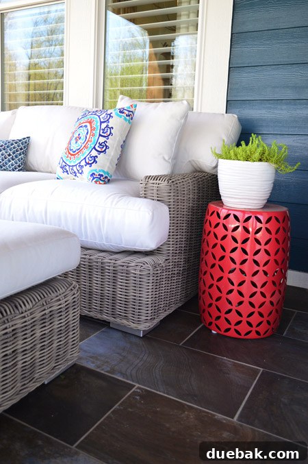 Close-up of the front porch details, showing decorative pillows, side table, and the dark porcelain tiles from The Tile Shop.