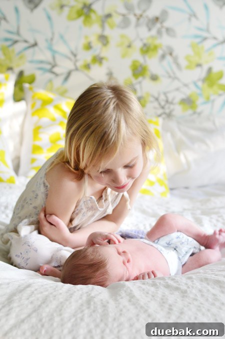 Big Sister Looking At Infant Baby Brother At DIY Newborn Photo Shoot