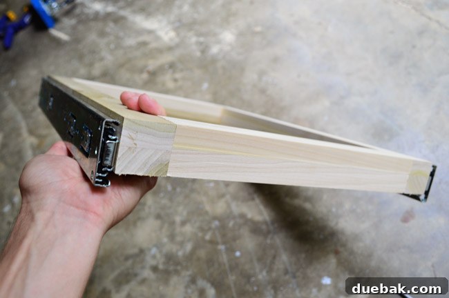 Close-up of the drawer rail attached to the bottom edge of the frame, showing precise alignment.