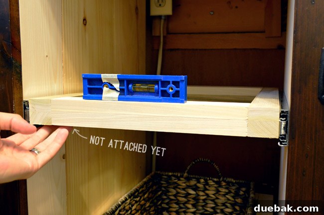 Checking the level of the drawer frame and slide before final attachment to ensure smooth operation.