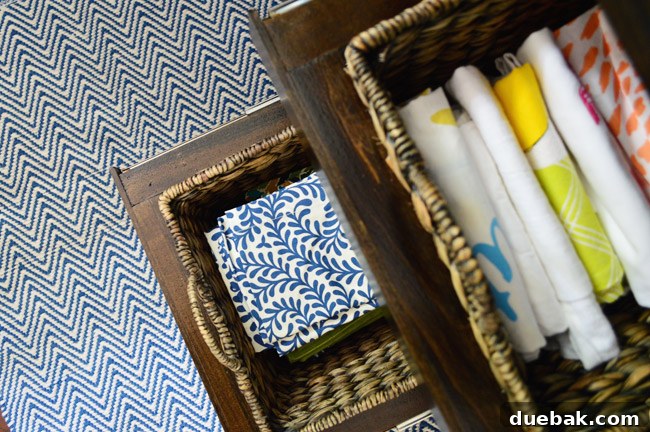 The completed slide-out basket storage, filled with dishtowels, paper, and cloth napkins.