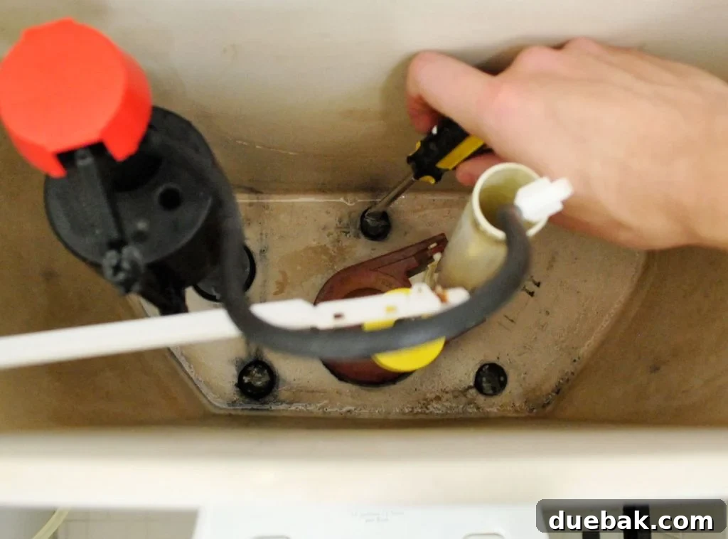 Hand Unscrewing Bolts Inside Toilet Tank