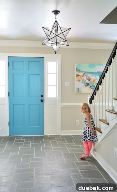 A vibrant beach painting by Teil Duncan, featuring beach umbrellas and figures, hangs above a console table in a stylish home entryway.