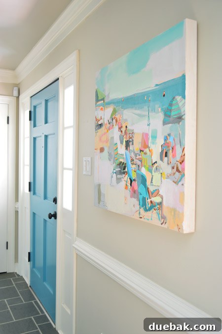 Teil Duncan painting hanging in a home entryway, with a blue front door visible and a wall painted in Edgecomb Gray.