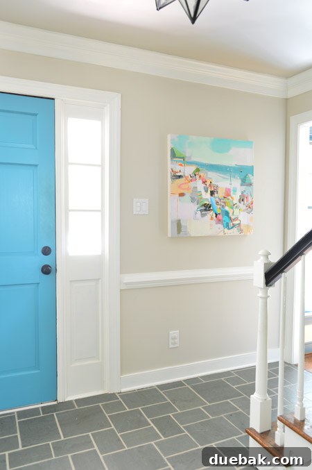 View of a home foyer with multiple paintings displayed, including the Teil Duncan beach art and two smaller pieces.