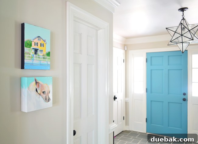 Close-up of two smaller paintings in a foyer, featuring a beach scene and a portrait of a dog.