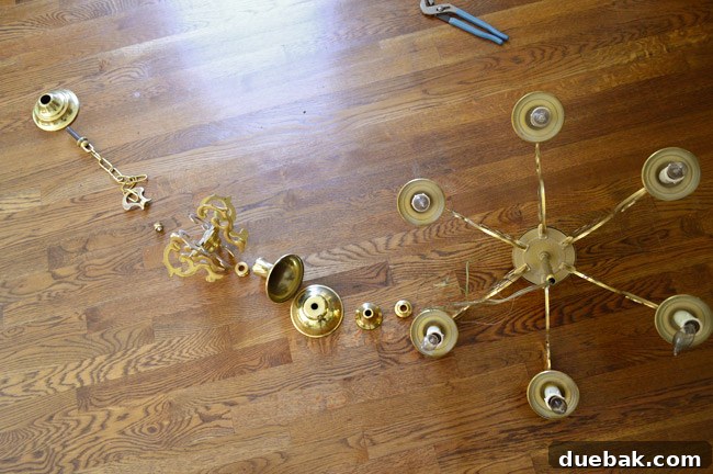 Disassembled chandelier components meticulously laid out in order on the floor for organized reassembly.